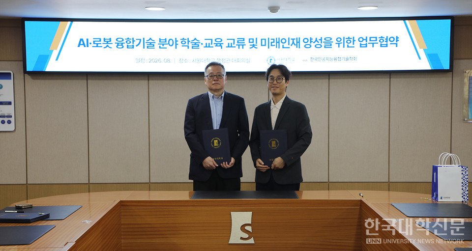 서원대와 한국인공지능융합기술학회가 'AI·로봇 융합기술 분야 학술·교육 교류 및 미래인재 양성을 위한 업무협약' 배경 화면 앞에서 협약서를 들고 있는 모습