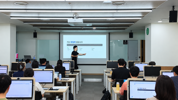 한국언론진흥재단 임직원 AX 실습교육 현장 — 강사가 화면을 가리키며 설명하는 PC 실습실