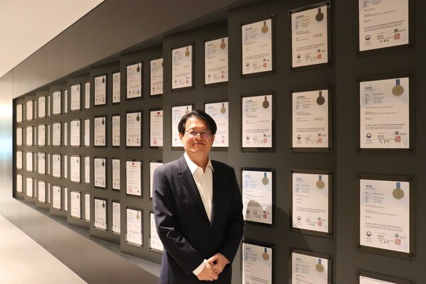 라온피플 관계자가 특허·인증서가 걸린 벽 앞에 서 있는 모습 (산업뉴스 제공)